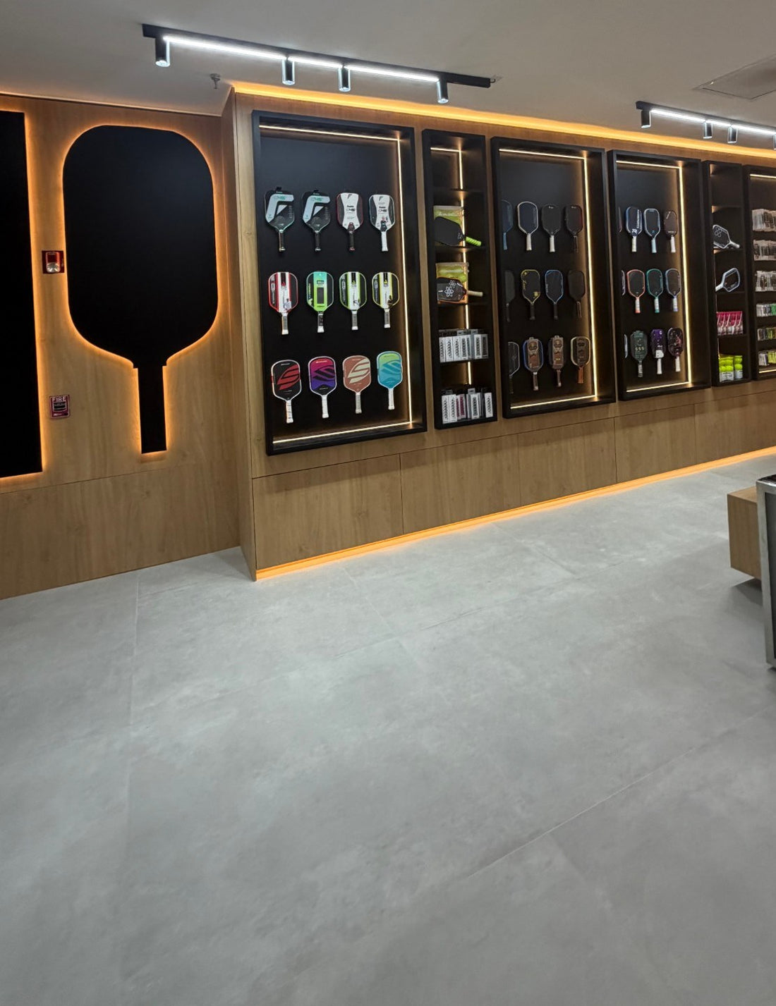 The demo paddle wall at Spinwave Boca: paddles in lit black display cases next to a large backlit paddle silhouette